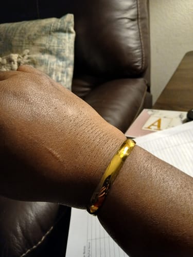 Close-up of a customer wearing a shiny, gold-colored bangle from the jewelry bundle on their wrist.