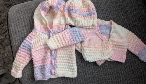 Customer's finished knitting project: a pastel hooded jacket, cardigan, and matching hat for a baby girl.