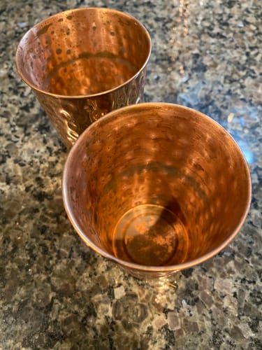 Customer's close-up of two hammered copper cups showing dark discoloration on the inside from use.