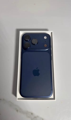 El iPhone 17 PRO azul de un cliente, visto desde arriba dentro de su caja blanca.