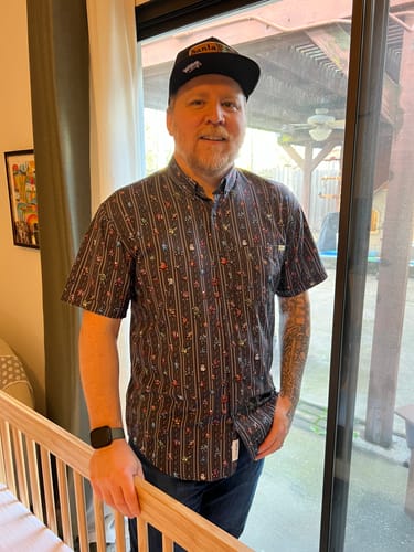 Reviewer standing indoors wearing the patterned Mega Man "Mega Pixels" KUNUFLEX short sleeve shirt.