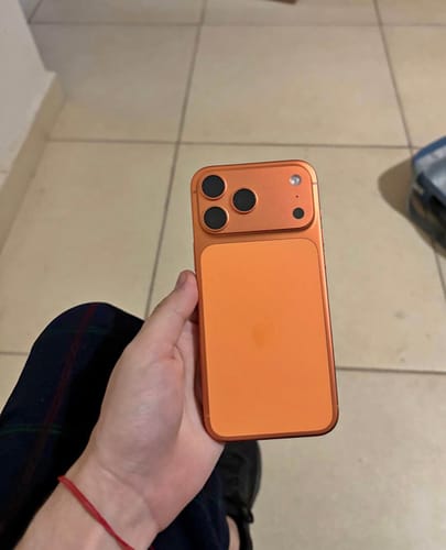 Cliente sosteniendo un IPHONE 17 PRO MAX color naranja, mostrando la parte trasera y las cámaras.