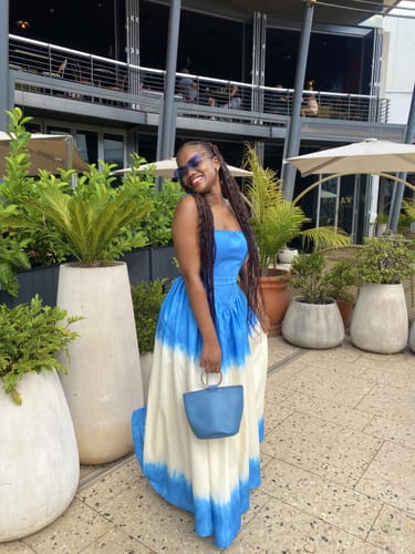 Customer smiling in the blue and white Corset Style Tie-Dye Maxi Dress on an outdoor patio.