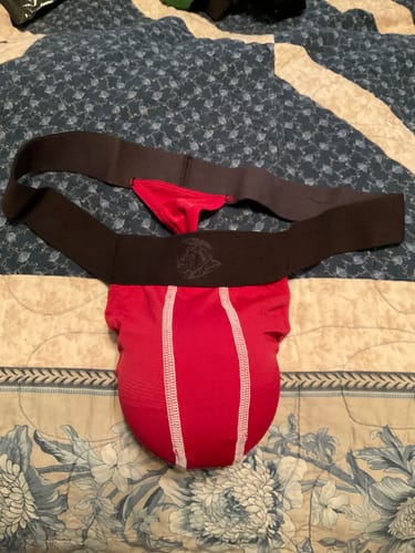 Customer's crimson Nylon Mesh Thong with a black waistband and white seams laid out on a bed.