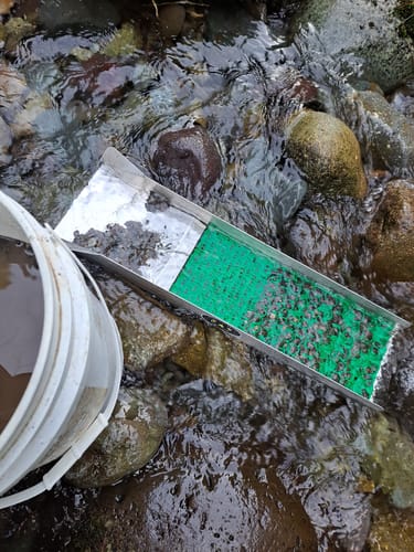 Customer's Trek Sluice Box with a green Dream Mat operating in a rocky, shallow stream.