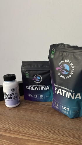 Un cliente muestra dos empaques de Creatina Monohidrato de diferentes tamaños sobre una superficie de madera.