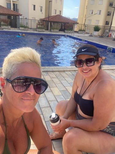 Cliente usando seus óculos Norma em uma selfie ao lado de uma piscina em um dia ensolarado.