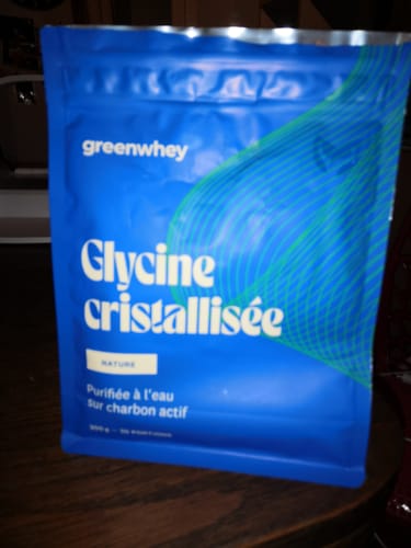 Client montrant le sachet bleu de Glycine cristallisée de la marque Greenwhey, posé sur une table.