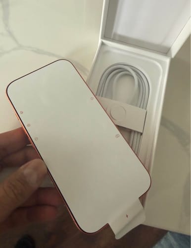 Cliente sacando el iPhone 17 PRO de su caja, aún con el protector de papel en la pantalla.