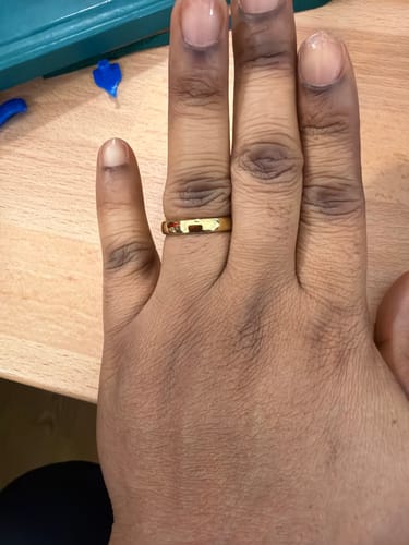 Reviewer showing their polished gold Elyos ring on their hand against a wooden surface.