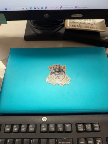 Customer's custom die-cut sticker with a white border applied to the center of a teal laptop.