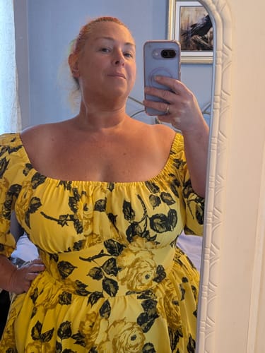 Reviewer's mirror selfie showing the upper portion of the vibrant yellow Vacation Dress with a vintage rose print.