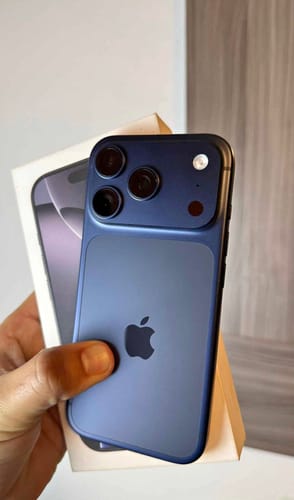Un cliente sostiene la parte trasera de un iPhone 17 PRO azul oscuro, con la caja blanca detrás.