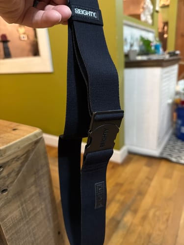Customer holding the black 80Eighty Resilient Belt, showing the buckle and stretchy material.