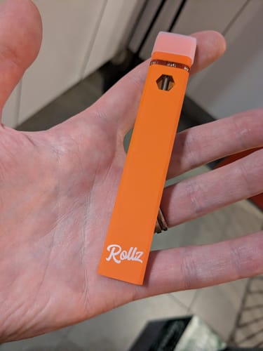 Customer holding the slim, orange ROLLZ THCA Vape in their hand.