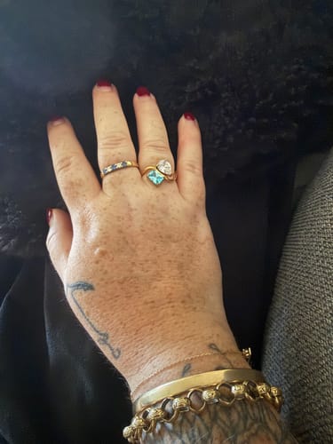 Reviewer's hand wearing the gold Navae Birthstone Ring with light-blue and clear stones.