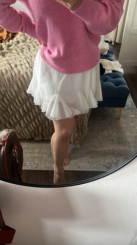 Kundin trägt den weißen, gerüschten Rock "Summer", kombiniert mit einem pinken Pullover.