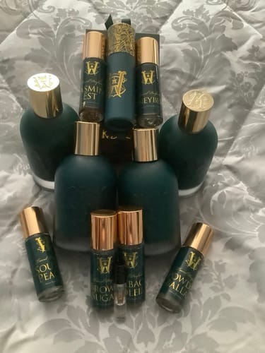 Customer's collection of dark teal fragrance bottles with gold caps, including spray and rollerball sizes.