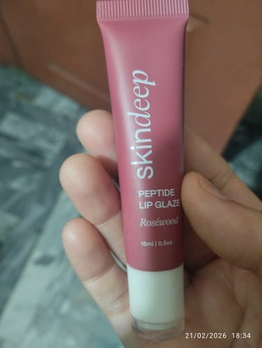Customer holding the pink tube of skindeep Peptide Lip Glaze in the shade Roséwood.