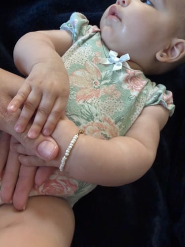 Close-up of a customer's baby wearing a delicate white beaded bracelet.