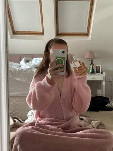 Reviewer holds up their bottle of Inspired by La Vie Est Belle - 144 perfume in a bedroom mirror selfie.