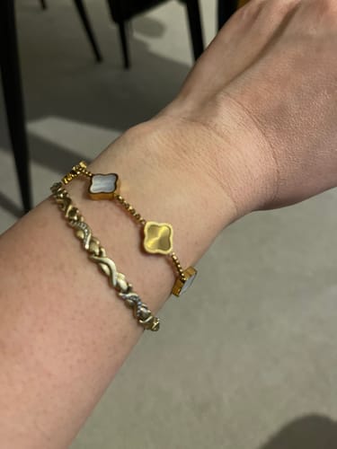 Customer's wrist wearing the gold Celine Clover Bracelet with mother of pearl and textured gold charms.