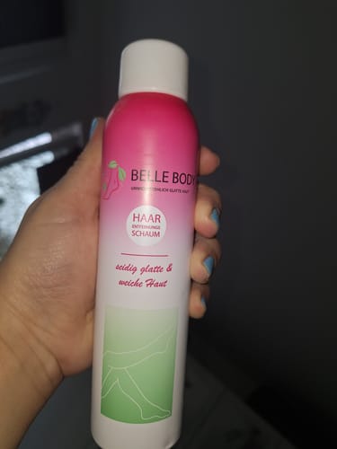 Ein Rezensent hält die rosa-weiße Dose des Haarentfernungsschaums in der Hand.