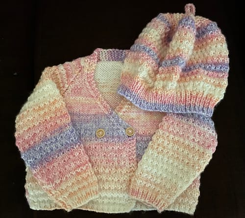 Reviewer's completed baby cardigan and hat, knitted in a pastel yarn from the mystery box.