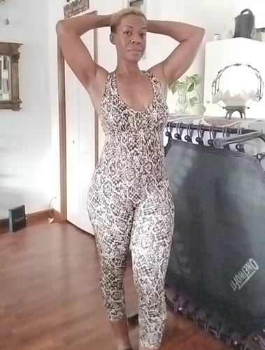 Reviewer posing indoors in the patterned Rise Racer Back Legging Jumpsuit, showing its form-fitting style.