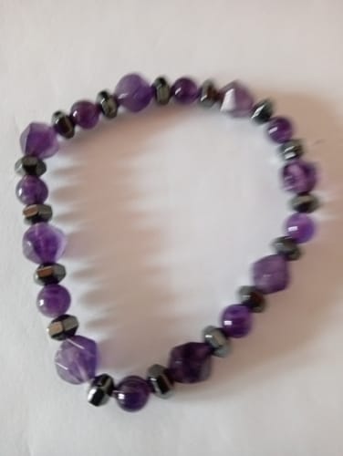 Photo d'un client montrant le Bracelet Améthyste avec des perles violettes et des perles d'hématite.