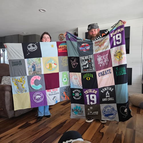Customers holding up their large, colorful Premium T Shirt Quilt made from many memorable shirts.