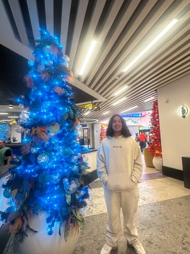 Customer wearing the off-white SAVD Oversized Hoodie and matching pants while standing indoors next to a Christmas tree.