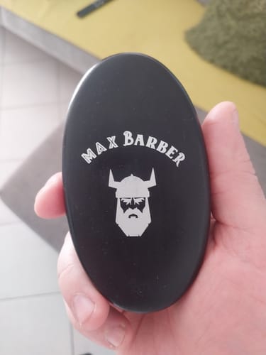 Client tenant la brosse à barbe noire dans sa main, avec le logo de la marque visible.