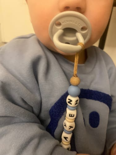 Cliente muestra un primer plano de su bebé usando el chupete DIAMOND gris.