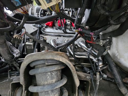 Customer's view of the shiny Exhaust Manifold Headers installed in the engine bay of a Chevy Silverado.
