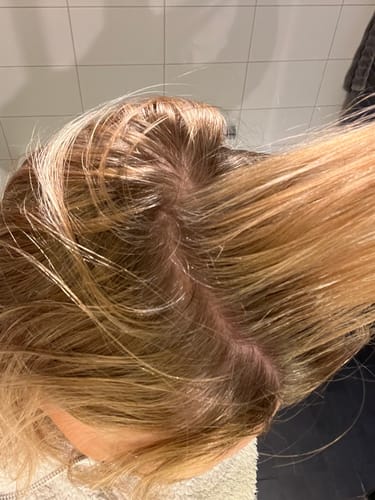 Close-up of a customer's hair parting, showing the results of the Starter Kit for Grey Cover on their roots.
