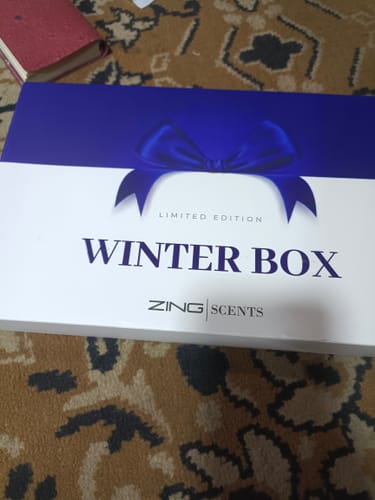Customer's white and blue 'Limited Edition Winter Box' from Zing Scents for their Sultan fragrance, set on a patterned rug.