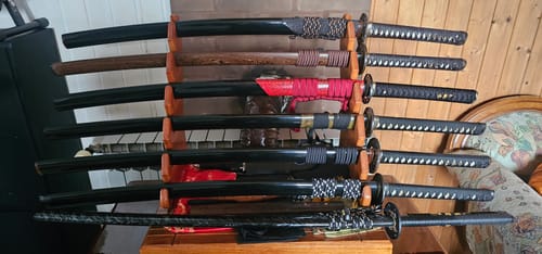 Customer's collection of several custom Japanese swords arranged on a wooden display stand.