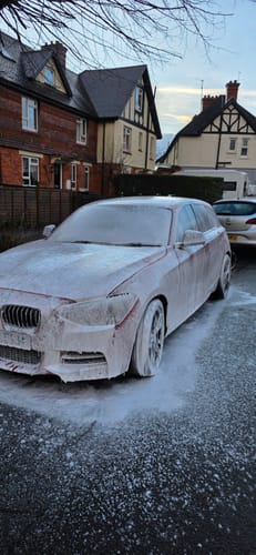 Customer's red car covered in thick white snow foam from the New MOAB kit during a wash.