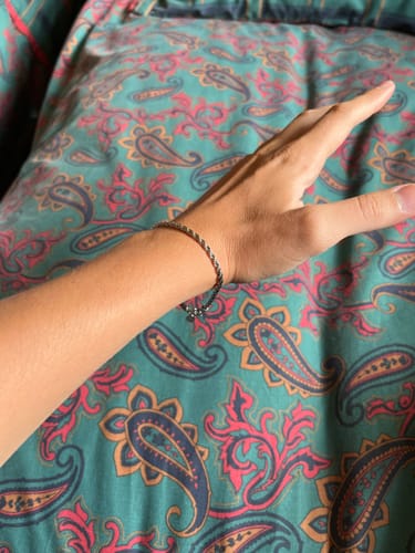 Cliente mostrando la Pulsera Rope 3mm en la muñeca sobre un fondo estampado.