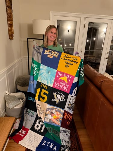 Customer holding up a large Premium T Shirt Quilt made from many colorful t-shirts.
