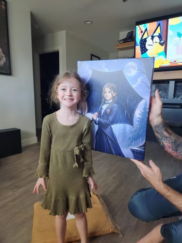 Reviewer holds up the personalized 'The Addams Princess' portrait next to a smiling child in a living room.