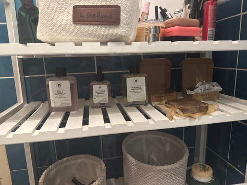 Customer's Soothing Toner on a white bathroom shelf, placed next to other skincare products.