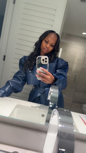 Reviewer taking a mirror selfie wearing the oversized, blue Vegan Leather Trench Coat.