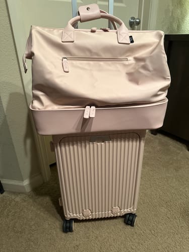 Customer's pink All-in-One Carry-On with a matching travel tote bag resting on the extended handle.