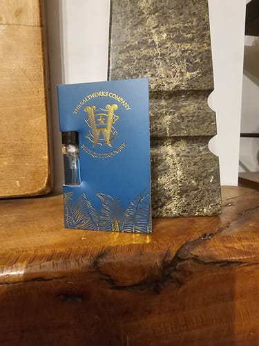 Customer's Honeyberry perfume sample in its blue and gold card holder, standing on a wooden surface.