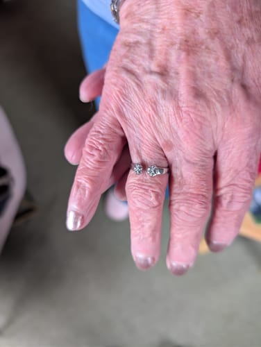 A customer's hand wearing the silver Paw Hug Ring wrapped around their middle finger.
