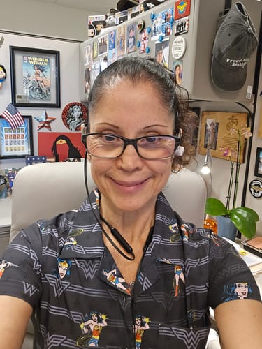 Reviewer smiling in an office while wearing the dark, patterned "Legacy of Wonder" women's shirt.