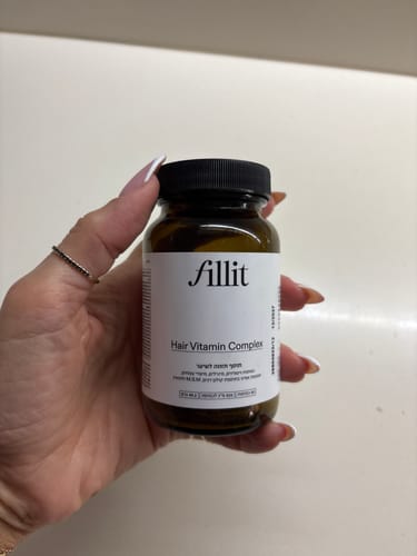 לקוחה מחזיקה בידה את בקבוק ויטמיני השיער של Fill it.