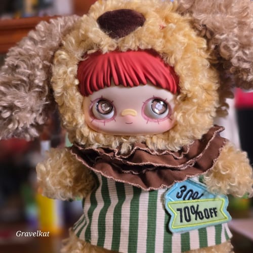 Close-up of a customer's Maymei Forgotten Funfair plush, showing its curly hood, striped shirt, and a '70% OFF' patch.